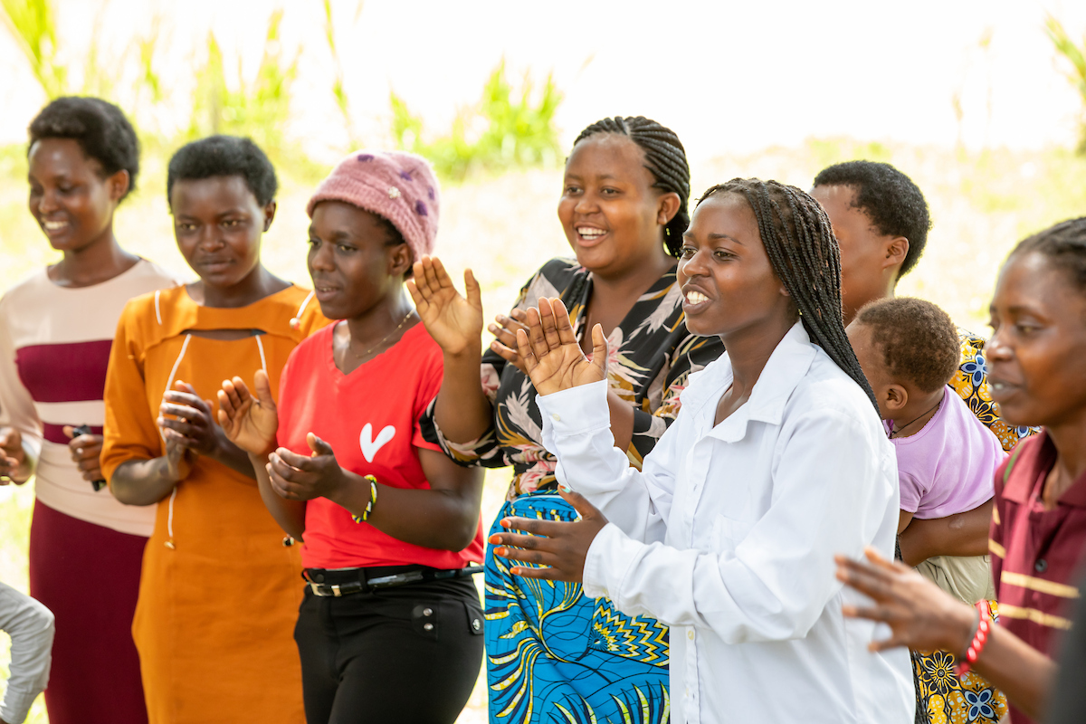 Group of women in Rwanda clapping and looking happy.
